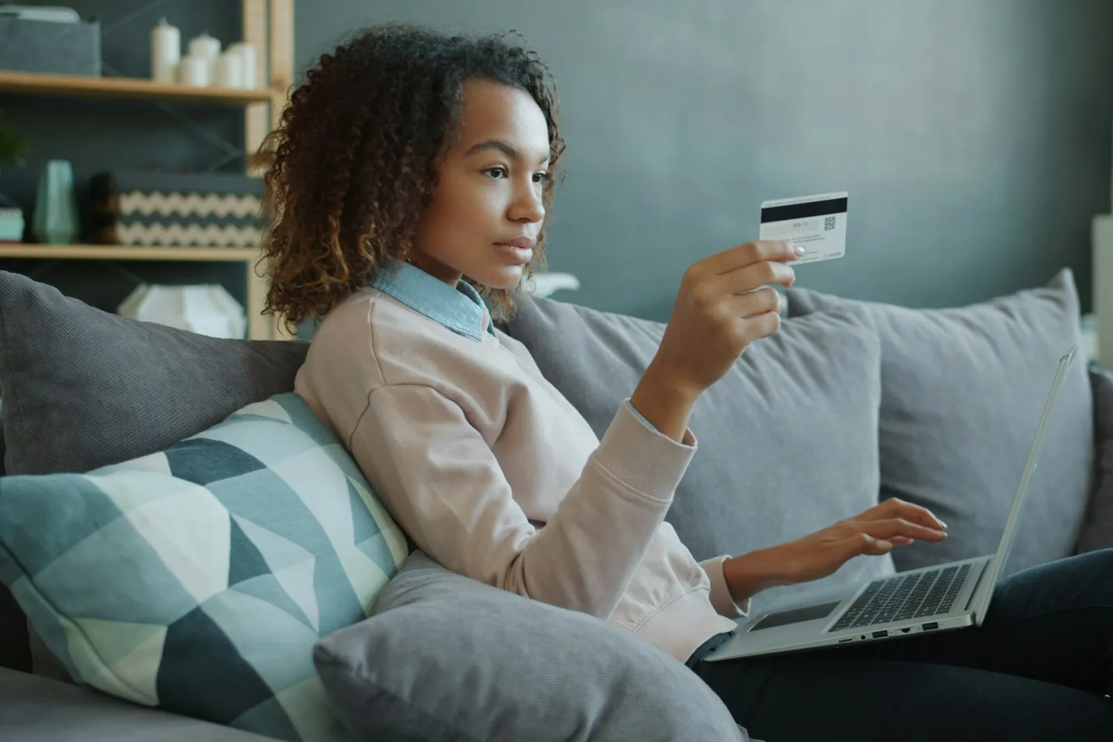 Woman relaxing on a sofa with a laptop and credit card, shopping online with Alaikas.com picks