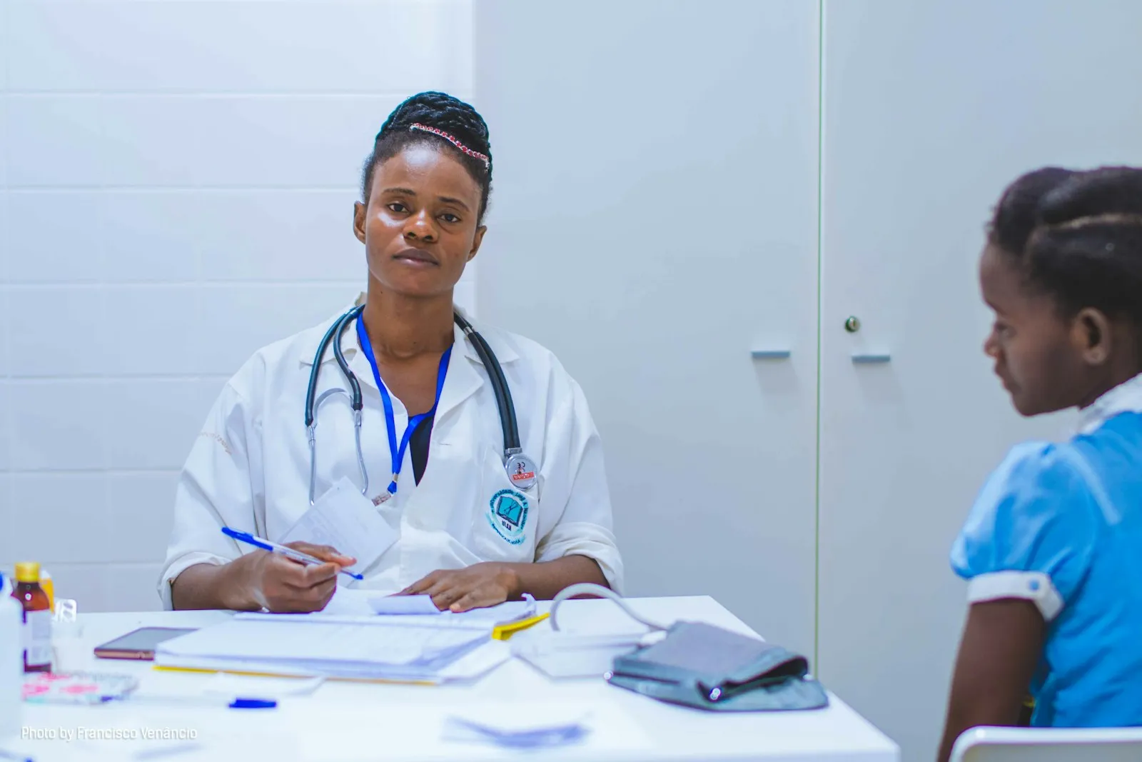 Family doctor at a desk talking with a young girl patient during a friendly clinic visit