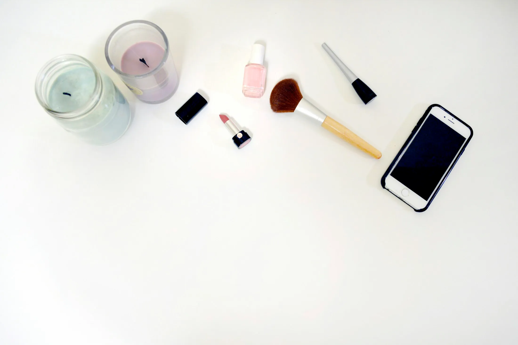 Flat lay of candles, nail polish, lipstick, makeup brush and a smartphone, the lifestyle, beauty and tech mix of Alaikas.com