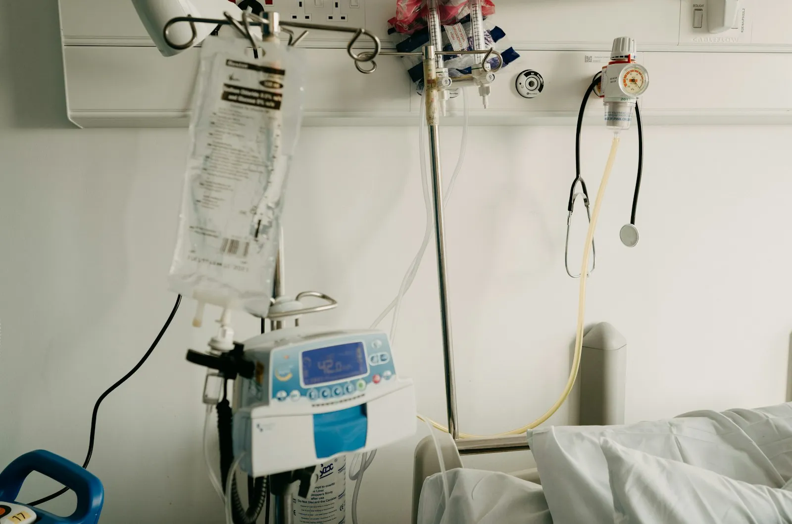 Intensive care unit bed surrounded by patient monitors, IV pumps and breathing equipment