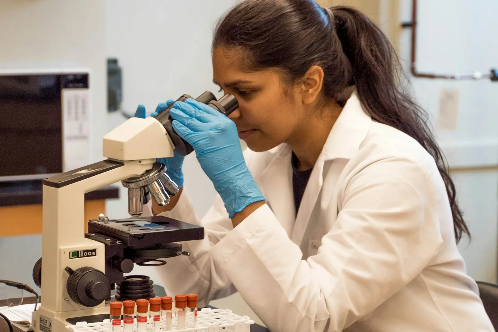 Laboratory scientist examining a sample under a microscope as part of medical laboratory testing