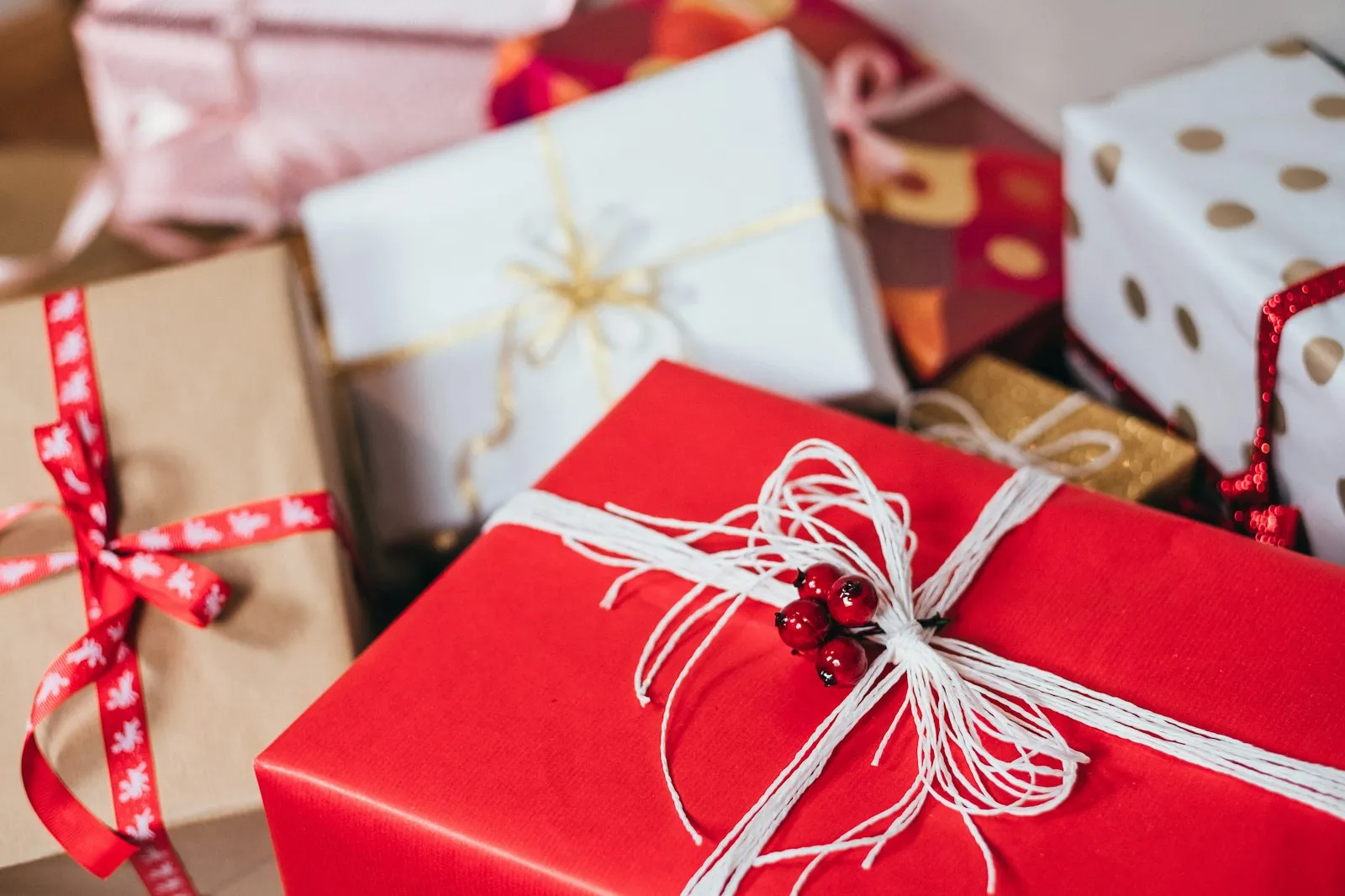 Pile of wrapped gift boxes with red paper and white string, from the Alaikas.com gift guide