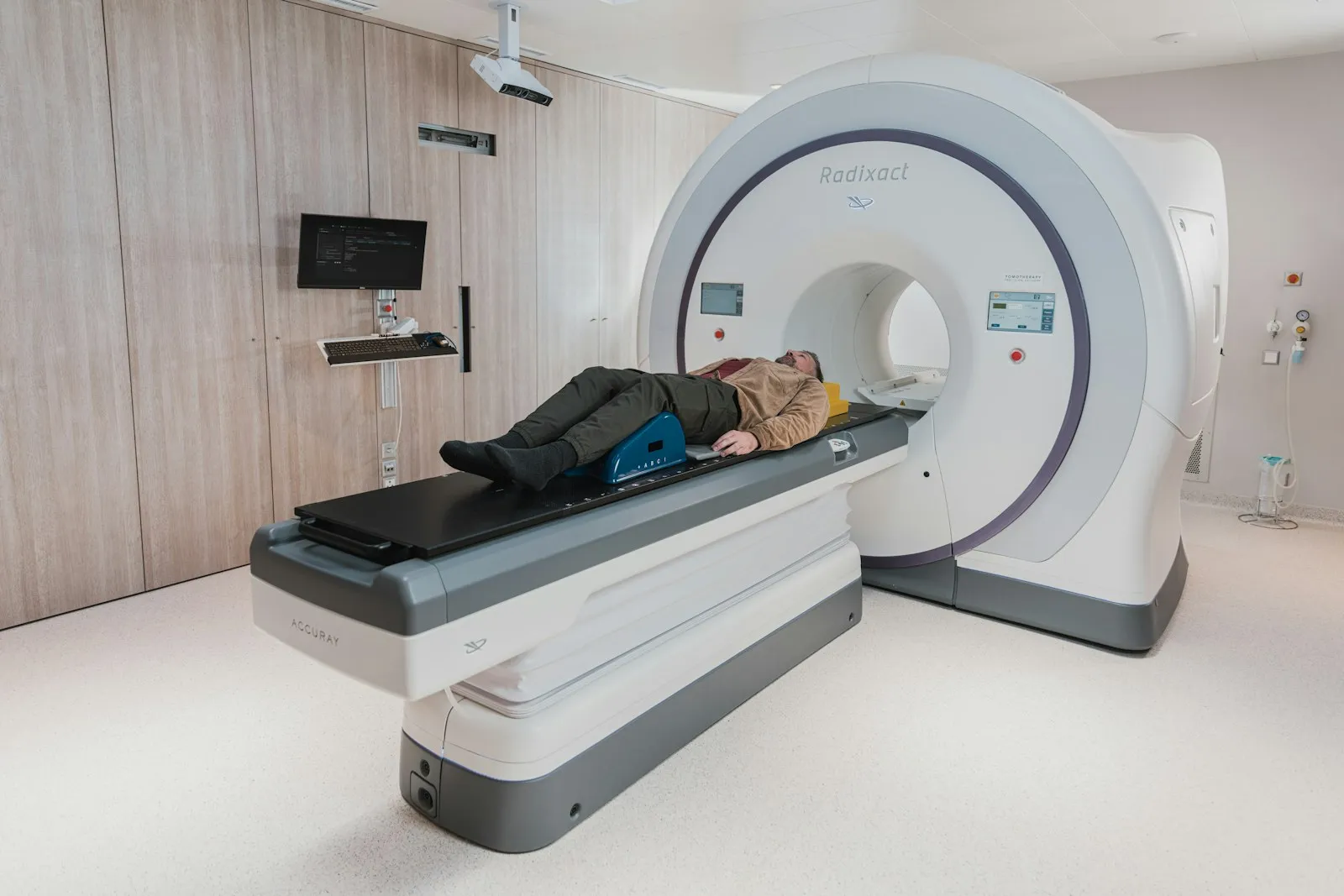 Patient lying on a CT scanner table while a radiology technologist prepares the imaging scan