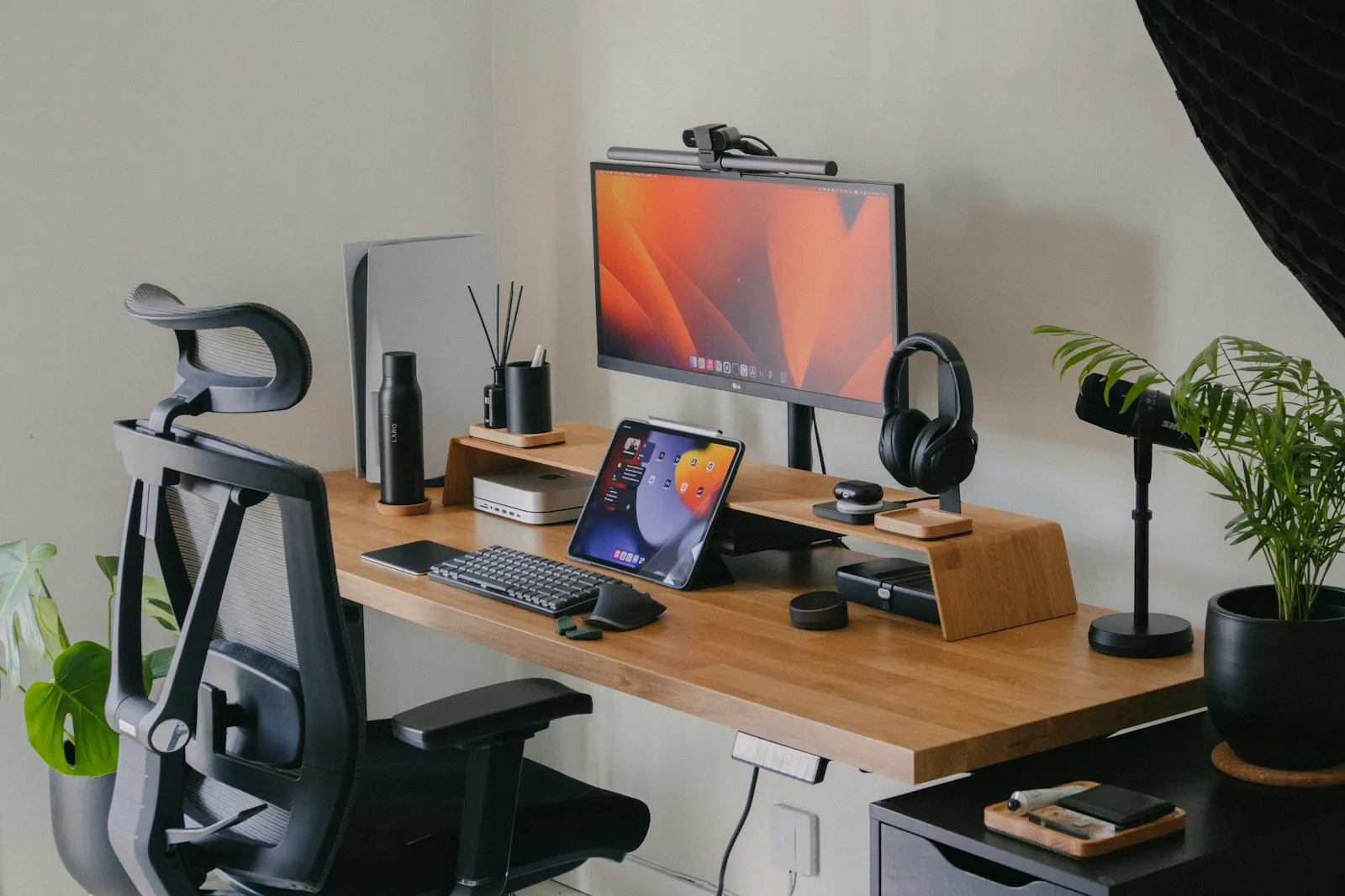 Clean home office desk with a monitor on a riser, keyboard and ergonomic chair, an Alaikas.com desk setup