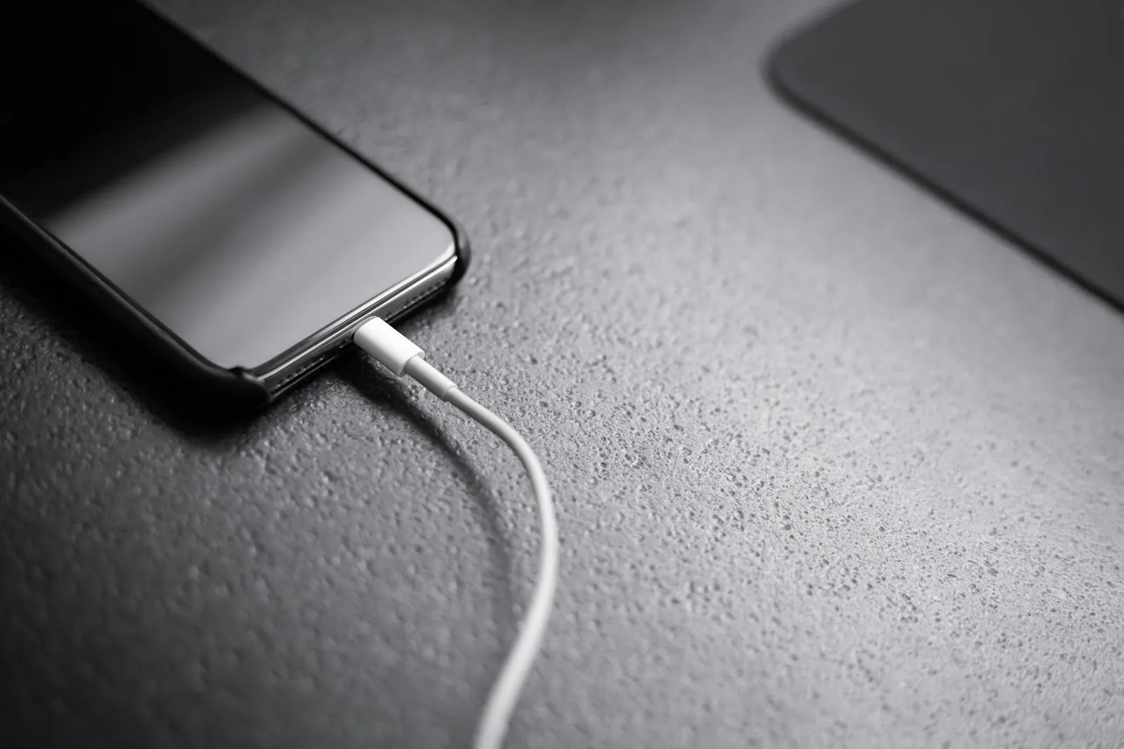 Black smartphone connected to a white charging cable, from the Alaikas.com phone accessories guide